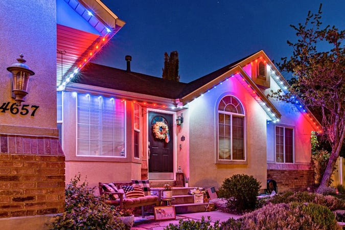 A close up picture of a home that has Trimlight 3L and is decorated with 4th of July decorations and has red, white and blue Trimlight lighting on the home.