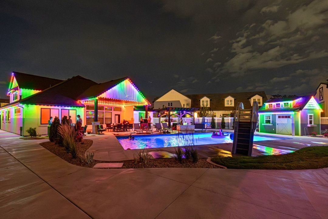 a backyard with a pool showing off a Halloween lighting pattern on the home and shed.