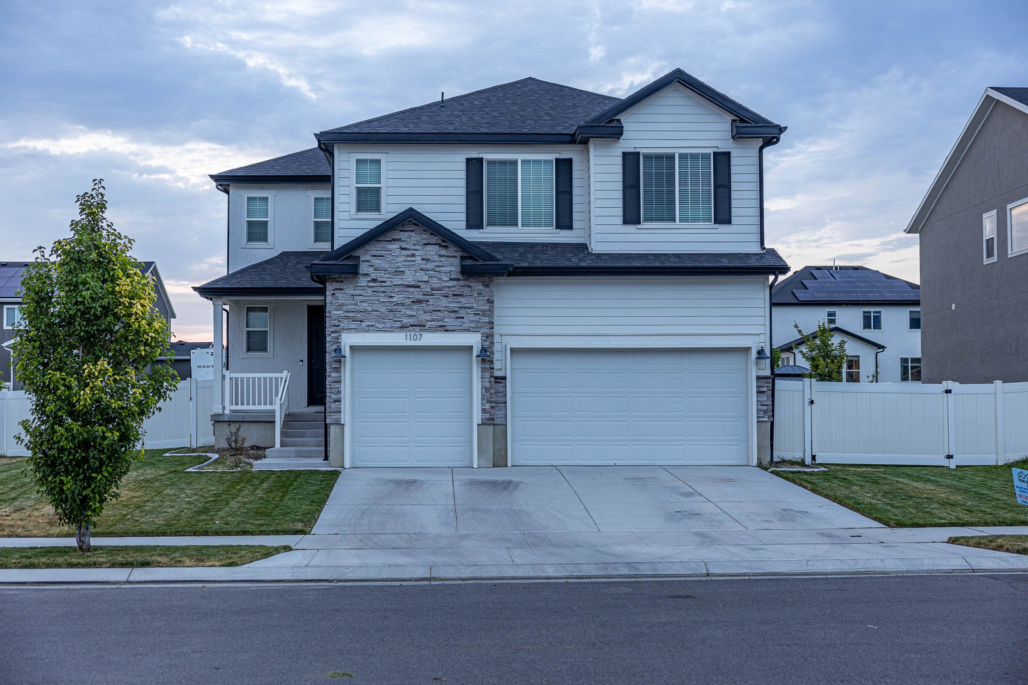 A home that has a white facia, a tree on the left with a dark roof
