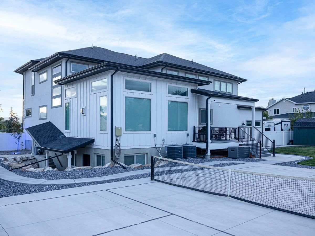 A home with a tennis net and a rockway pathway.