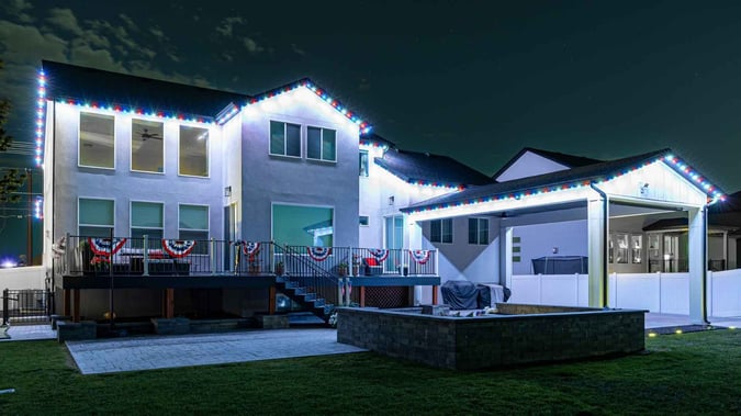 A picture of a home with patriotic decor around the home, featuring a 1 color per light pattern of red, white and blue