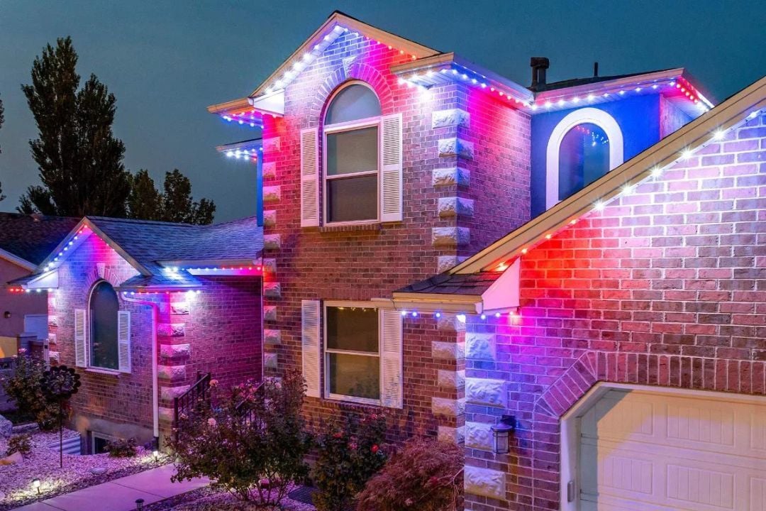 A home that is more of closer up shot of the home with brick. The home has a red, white and blue Trimlight pattern.