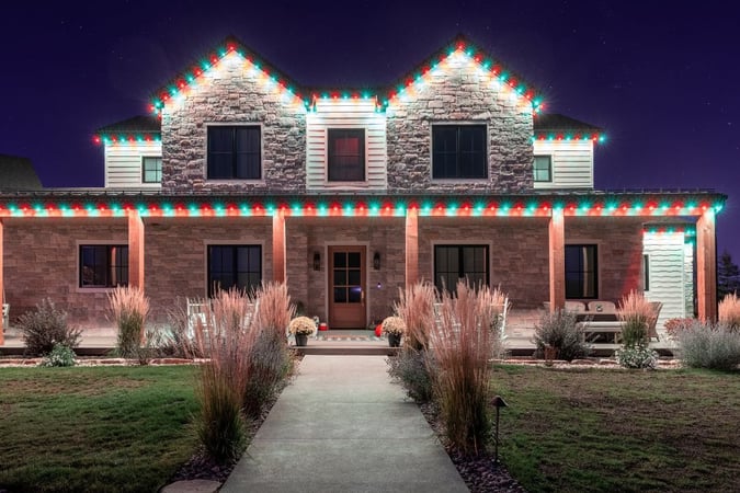 Trimlight Red and Green Christmas lights on rustic mountain home.