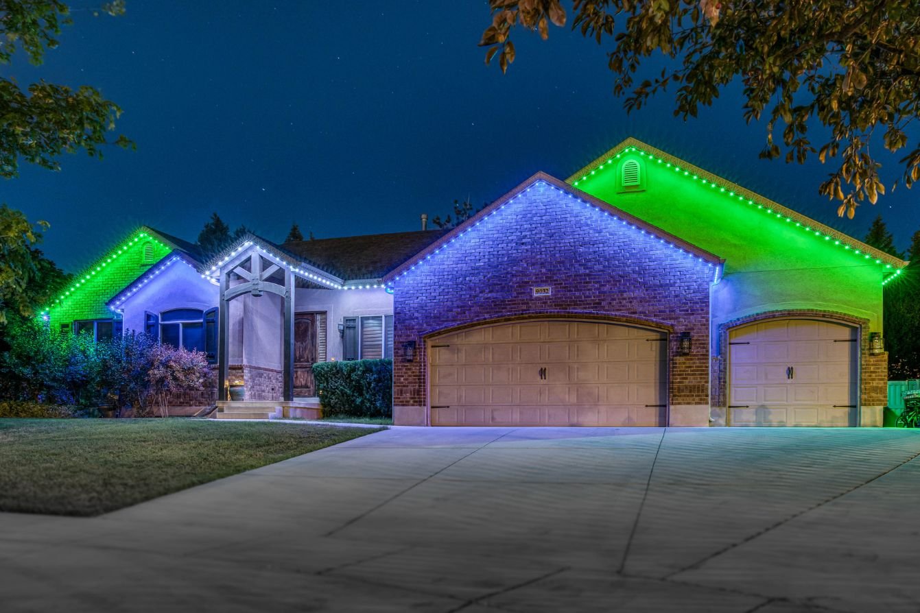 A home with many roofline peaks that has Trimlight LEDs in a blue, white and green zoning pattern.