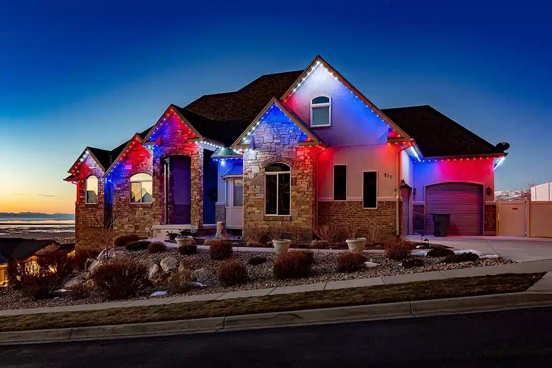 A home with a red white and blue pattern with some bush in the front.