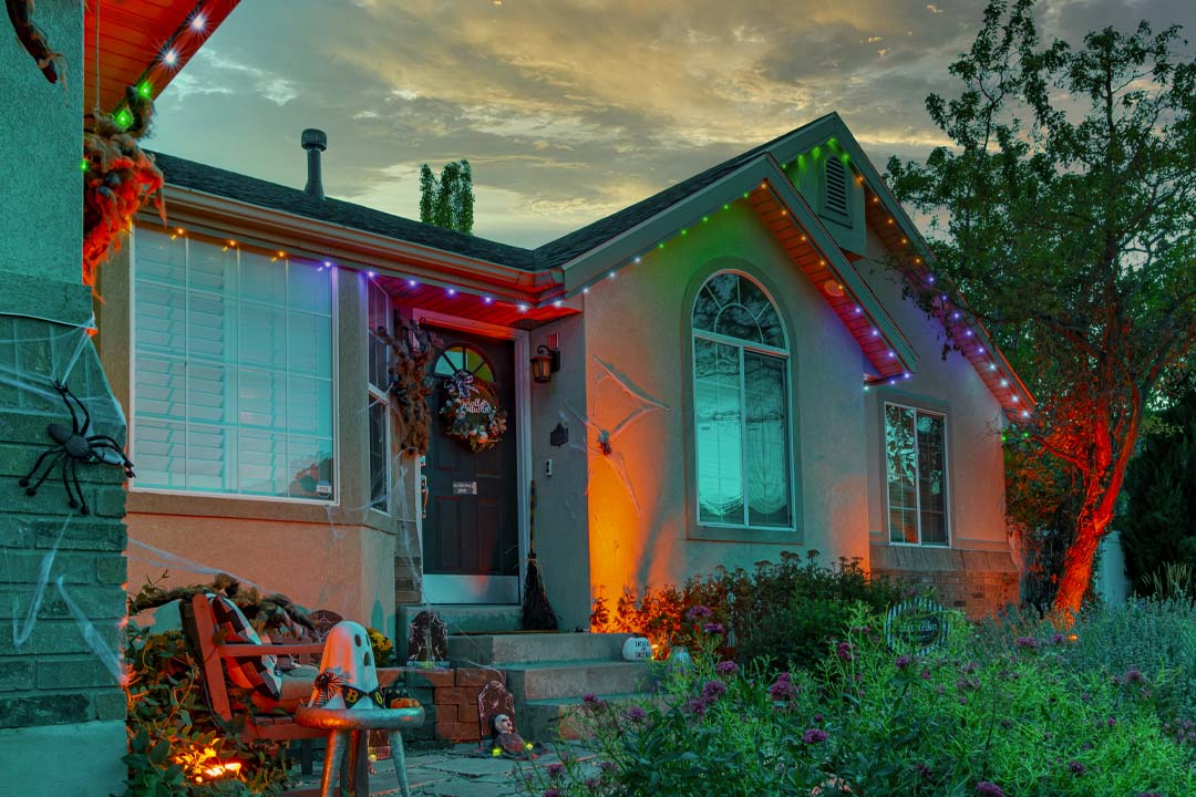 Halloween lighting and decor on a tan home