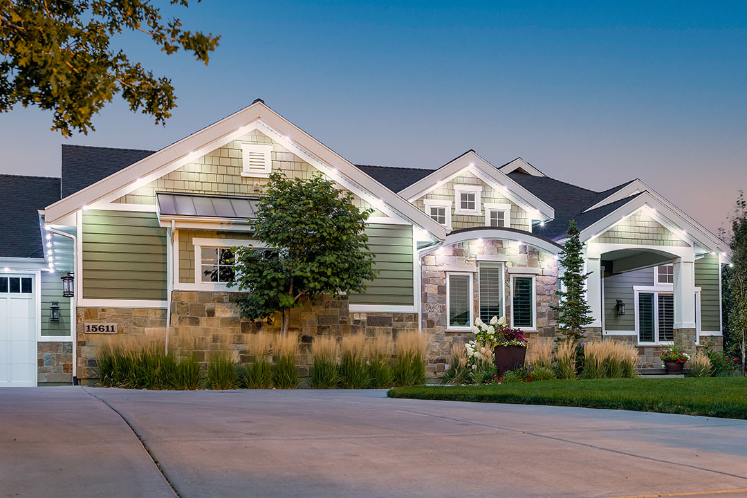 a modern home with white LED trimlight security lighting on the home. It has a big driveway with trees in front of the house.