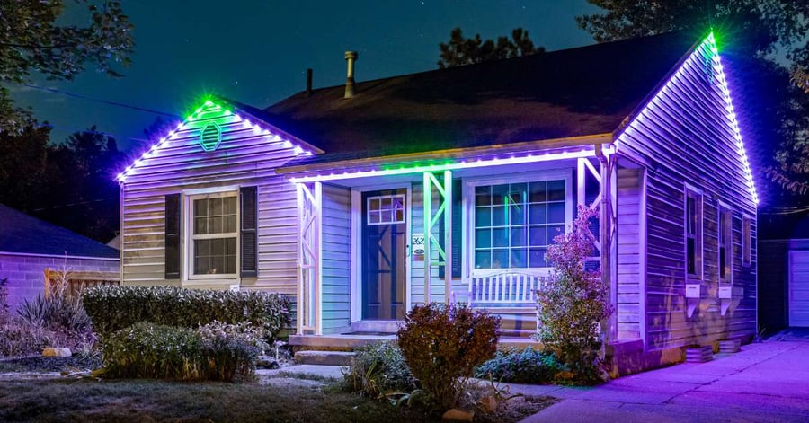 Cozy bungalow with green and purple outdoor Halloween lights on