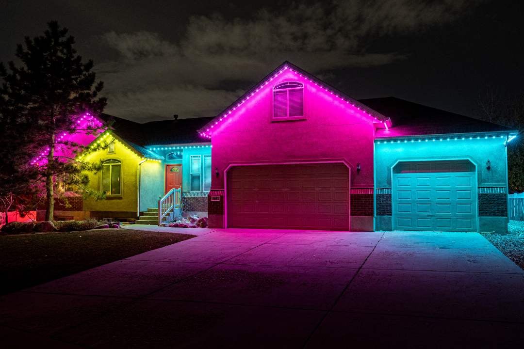 Suburban home with yellow, pink, and cyan blue zone lighting underneath soffit.