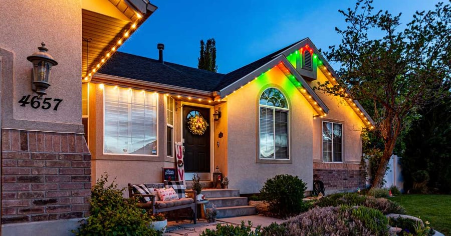 Outdoor holiday lights on one story home with holly color pattern on roof peaks