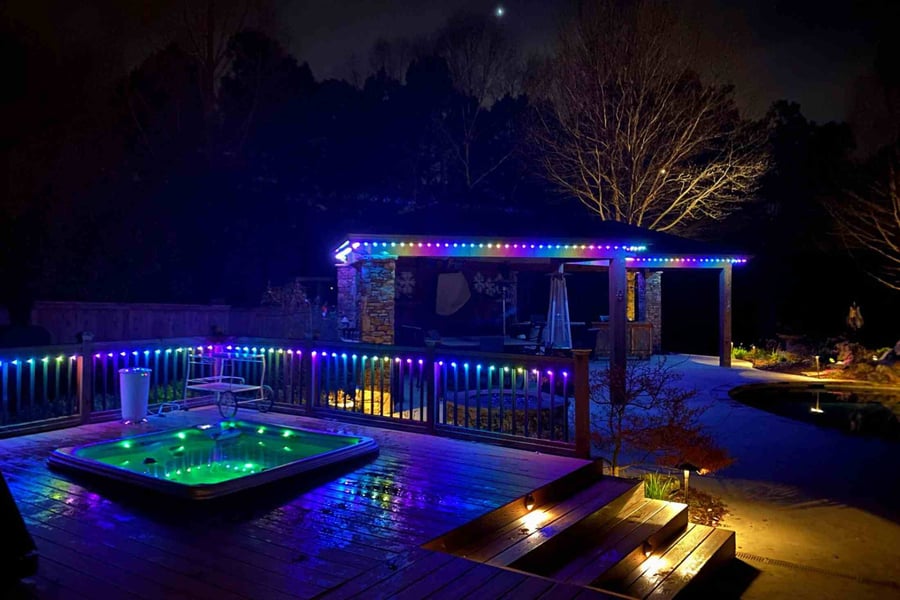 Hot tub surrounded by colorful lighting on deck