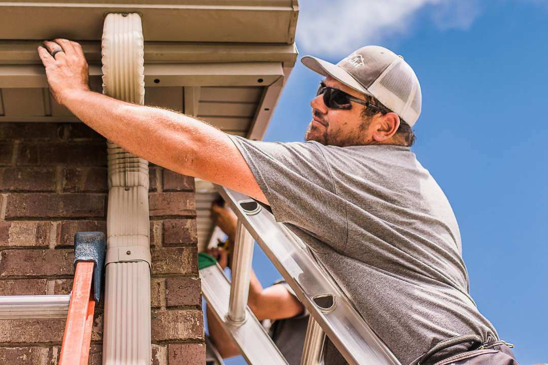 Trimlight dealer installing channel and trimlight lights on light brown soffit of home