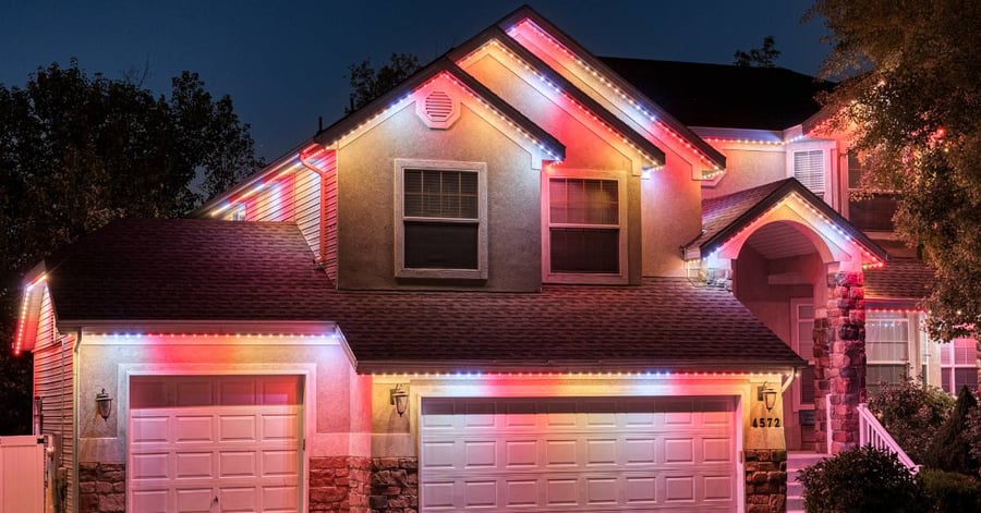 Stucco house with orange, yellow, and white holiday lights on trim