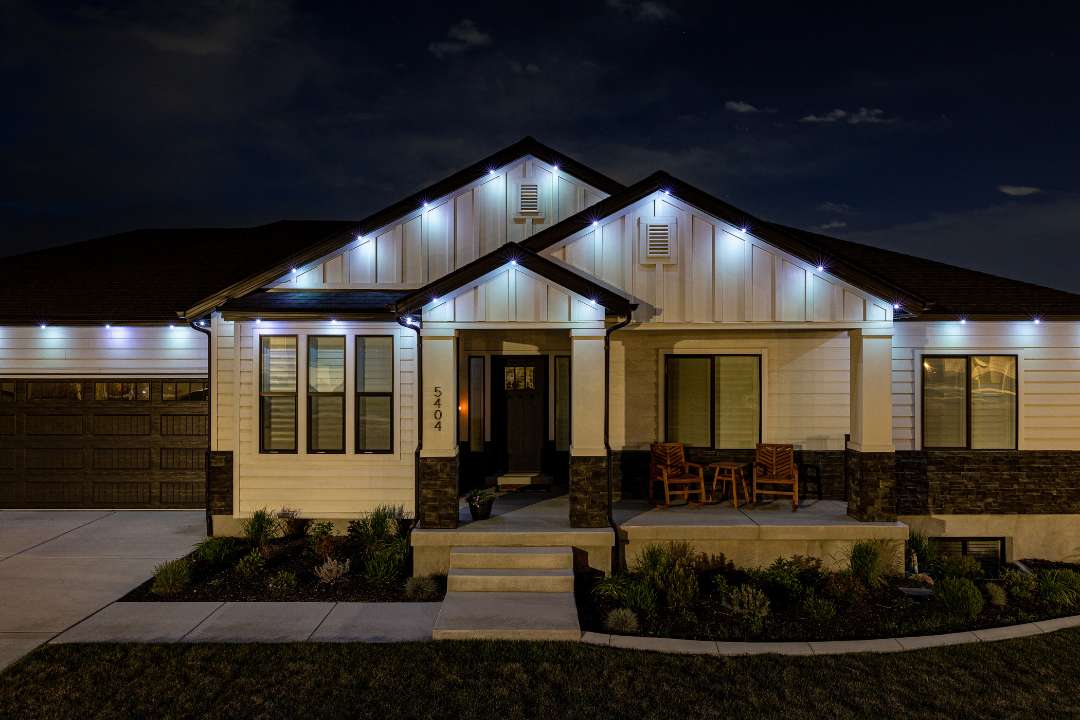 Security lighting on modern white home with black trim with rocking chairs on front patio